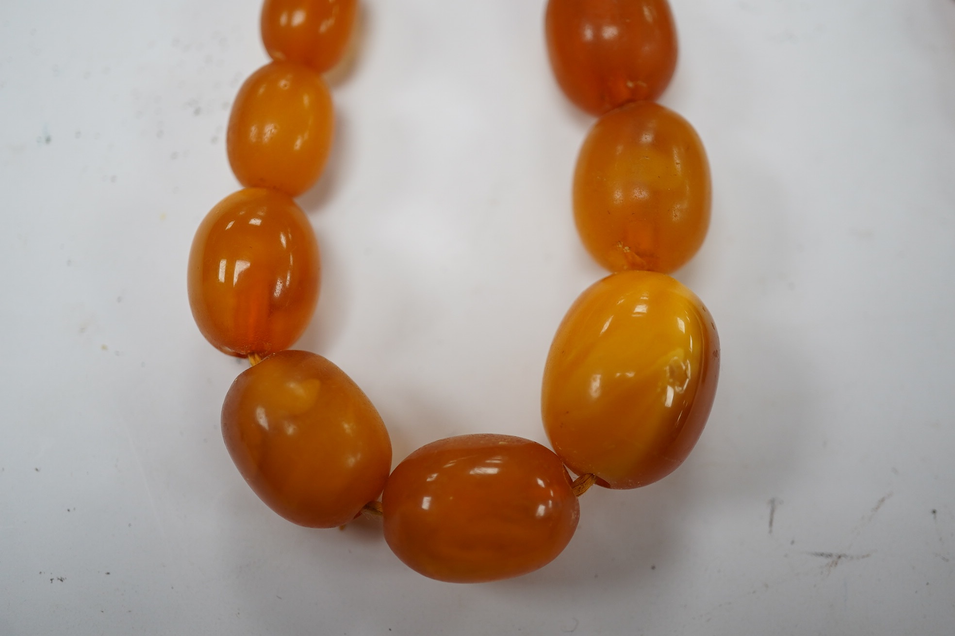 A single strand graduated oval amber bead necklace, 58cm, gross weight 34 grams. Condition - poor to fair